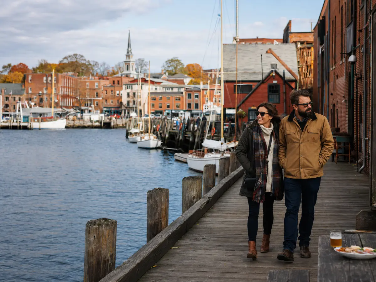 A couple walks Salem's historic harbor wharf in crisp autumn light.