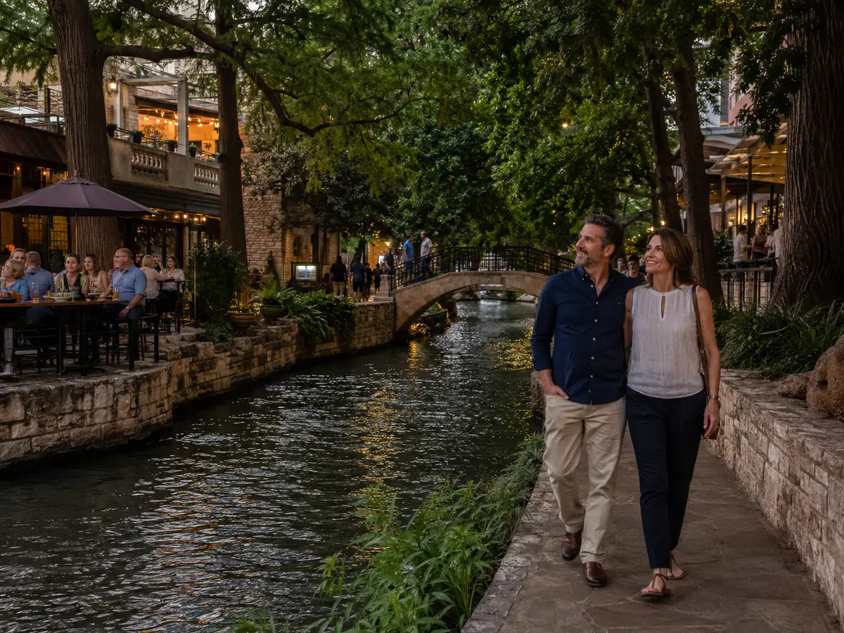 A couple walks beside the shaded San Antonio River Walk in the early evening.